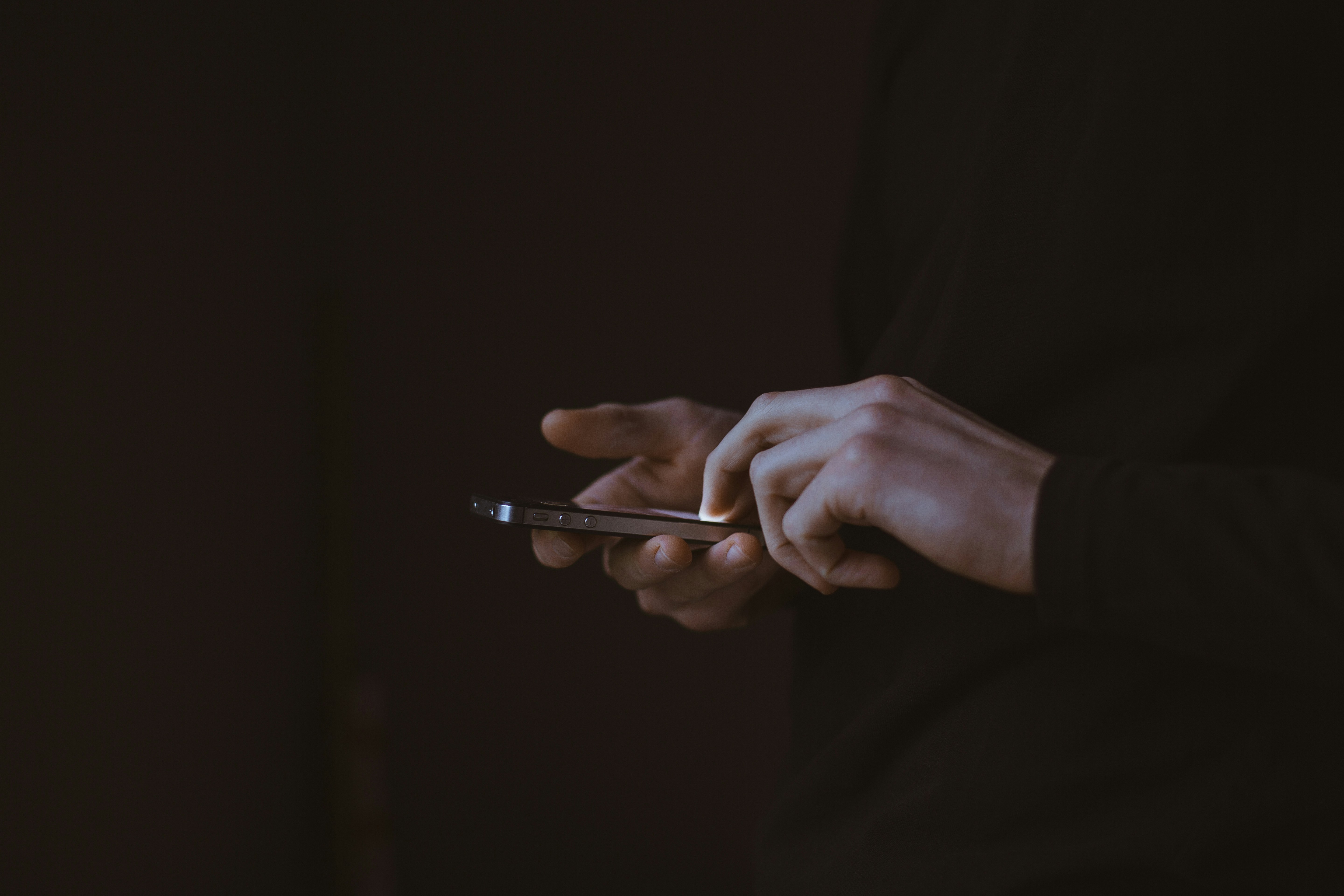 Hands using a smartphone against a dark background